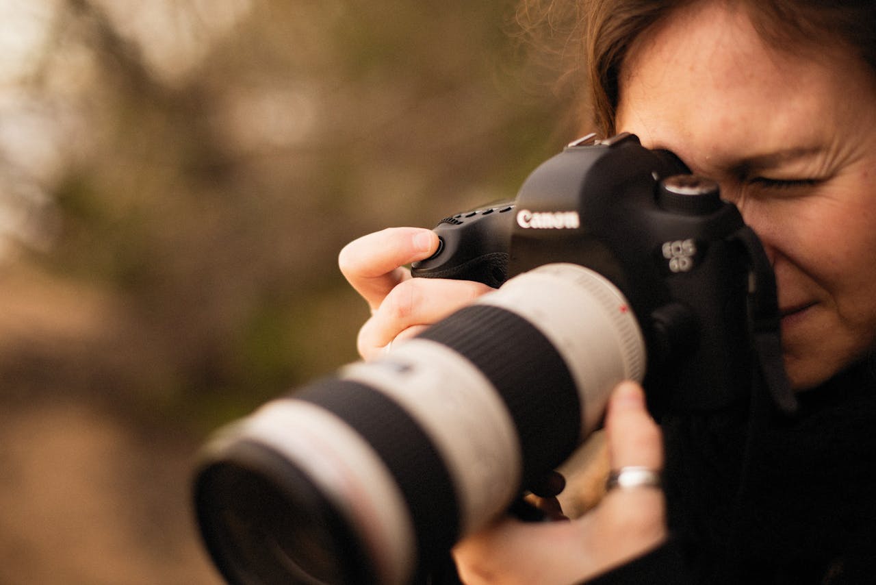 Close-up of female photographer using a DSLR camera outdoors.